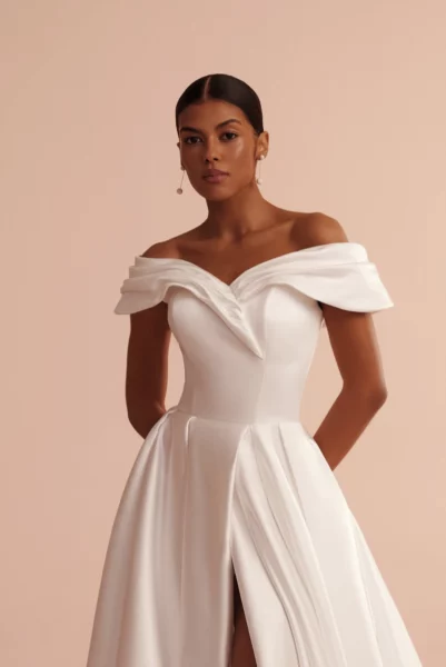 Schlichtes Brautkleid L426 Ariamo Light mit Carmen-Ausschnitt, elegantenTrägern und elegantem Schlitz – perfekt für kirchliche Hochzeiten oder Industrial Weddings in Hamburg und Lüneburg.