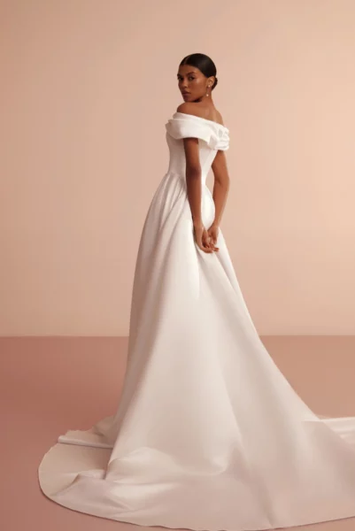 Schlichtes Brautkleid L426 Ariamo Light mit Carmen-Ausschnitt, elegantenTrägern und elegantem Schlitz – perfekt für kirchliche Hochzeiten oder Industrial Weddings in Hamburg und Lüneburg.