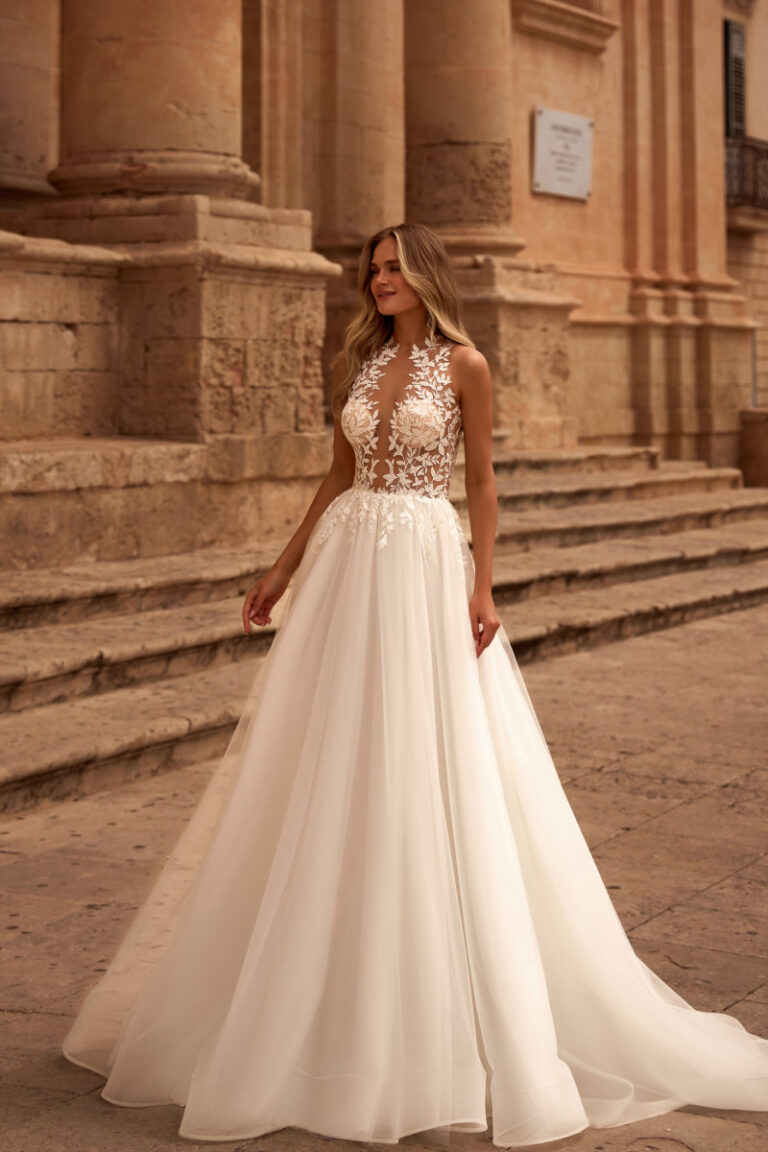 BANTA Brautkleid mit tiefem Illusionsspitzen-Ausschnitt – Brautmode Winsen, Braut vor historischen Steintreppen