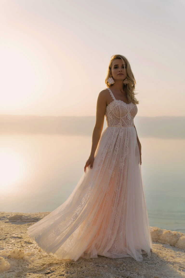 Bjork Brautkleid von Dama Couture mit Spaghettiträgern im Lingerie-Look – Brautmode, Vorderansicht am felsigen Strand