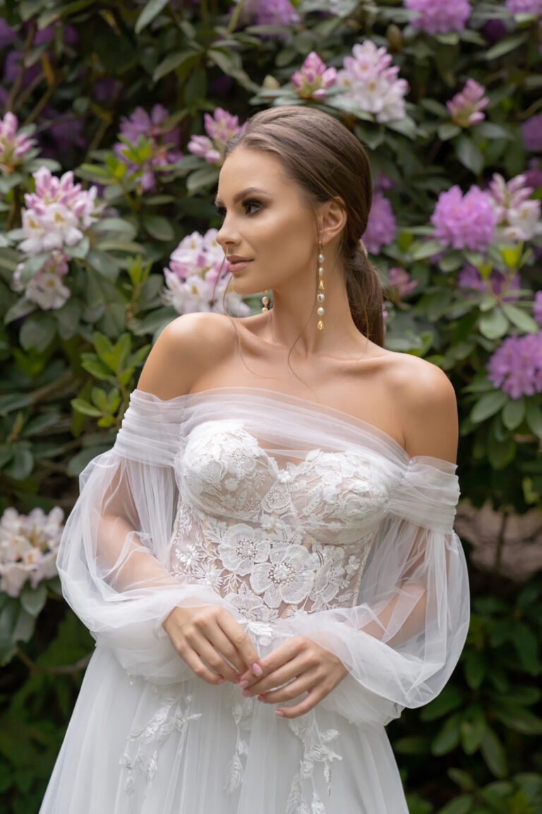 Boho-Brautkleid Lanka von Dama Couture mit Off-Shoulder-Ärmeln und Blumenspitzen-Korsage – Brautmode, Nahaufnahme im Blumengarten