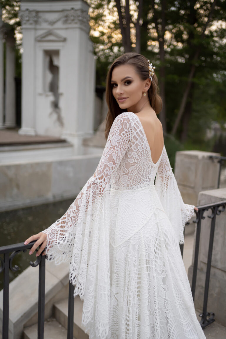 Boho-Brautkleid Lea von Dama Couture mit Häkelspitze, Fluegelärmeln und V-Rückenausschnitt – Brautmode, Braut am Brunnen im Park