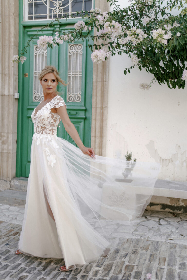 Brautkleid Lente von Dama Couture mit Spitzenoberteil und leichtem Tuellrock – Brautmode, Braut in Bewegung vor grüner Tür mit Rosen