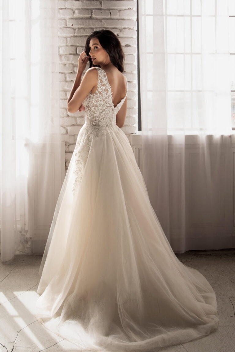 MAKENA Boho-Brautkleid mit Spitzenrücken und langer Schleppe – Brautmode Lüneburg Hamburg, Rückenansicht am Fenster
