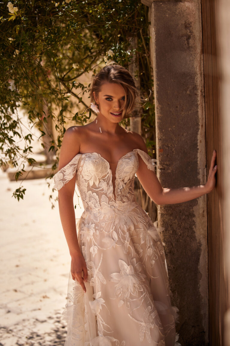 Nenufar Boho-Brautkleid mit 3D-Blumenspitze und Off-Shoulder-Ausschnitt – Brautmode Hamburg, Braut lächelnd im Freien