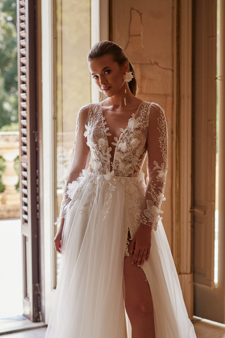 Octavia Boho-Brautkleid von Dama Couture – Brautmode Hamburg Lüneburg, Vorderansicht mit Spitzenärmeln am Fenster